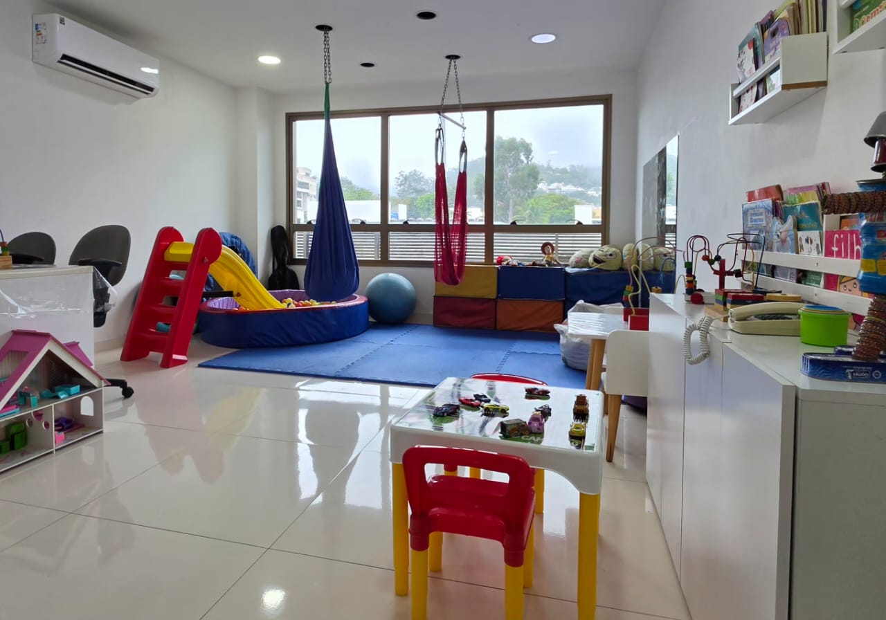 Sala ampla e luminosa da Conv!vi, com brinquedos, livros, mesa infantil e espaços para explorar